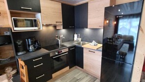 A compact kitchen with a microwave, coffee maker, and a black refrigerator. - Charming renovated apartment with Wifi and pets allowed, in the center of Les Gets (Les Gets)