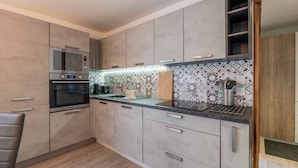 Une cuisine moderne avec des armoires grises, un four encastré, un four à micro-ondes et un revêtement mural décoratif.