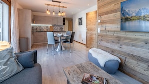 Un salon moderne avec un mur d’accent en bois, un coin repas avec une cuisine en arrière-plan et une grande fenêtre.