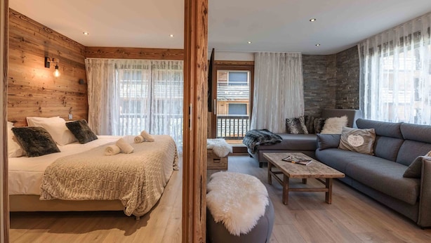 Une pièce confortable avec un lit, un canapé, une petite table et un plancher en bois.