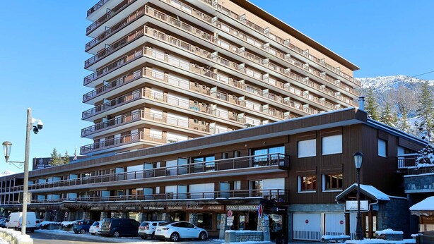 A multi-story hotel with balconies, a restaurant, and a parking area. - Slope-side studio in Courchevel 1650 - Terrace with view (Courchevel)