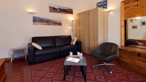 A room with a black leather sofa, a wooden cabinet, a black chair, and a patterned rug. - Slope-side studio in Courchevel 1650 - Terrace with view (Courchevel)