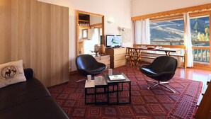 A cozy living room with a sofa, two black chairs, a coffee table, a television, and a dining area with a table and chairs. - Slope-side studio in Courchevel 1650 - Terrace with view (Courchevel)