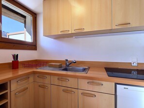 Eine Küche mit Holzschränken, einem Spülbecken und einem Geschirrspüler von Bosch.