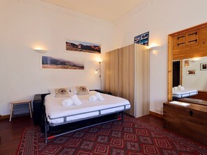Ein Schlafzimmer mit einem Bett, einem Holzschrank, einem Spiegel und zwei Wandleuchten.