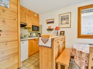 Une cuisine chaleureuse avec des meubles de rangement en bois, un four à micro-ondes et un coin repas comprenant une table et un banc.