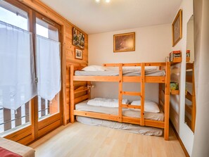A bunk bed room with wooden walls, a window with curtains, and a bookshelf with books. - Apartment in Morzine, 4 ppl, near cable cars (Morzine)