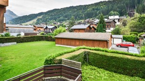 A residential area with wooden houses, a green lawn, and a mountainous backdrop.