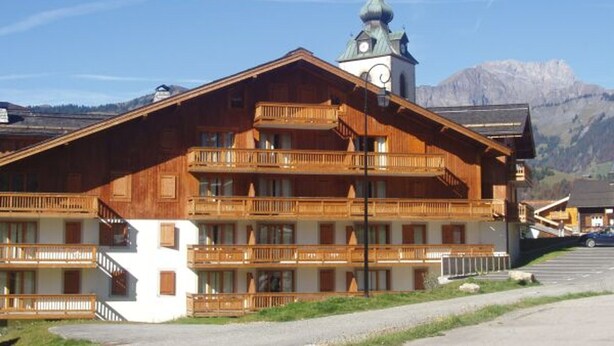 A wooden building with multiple balconies and a clock tower.