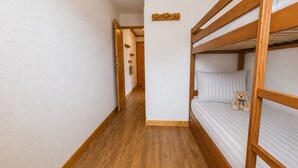 A narrow hallway with wooden flooring and bunk beds on one side. - Village center apartment with pool and terrace (Notre-Dame-de-Bellecombe)