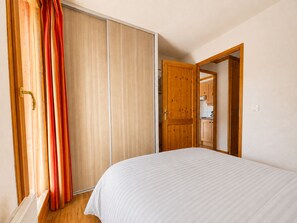 Een slaapkamer met een bed, een kledingkast en een deur naar een keuken.