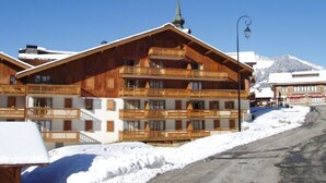 A wooden chalet-style hotel with multiple balconies and a mountain backdrop.