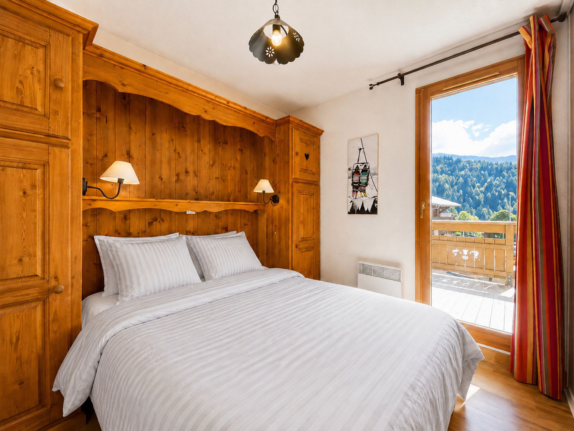 A wooden bedroom with a bed, two wall-mounted lamps, a radiator, and a window with curtains.
