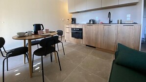 A compact kitchen with a dining area, featuring a round table, chairs, and a built-in oven. - Modern 2-room apartment + cabin, 4 persons, parking (Cohennoz)