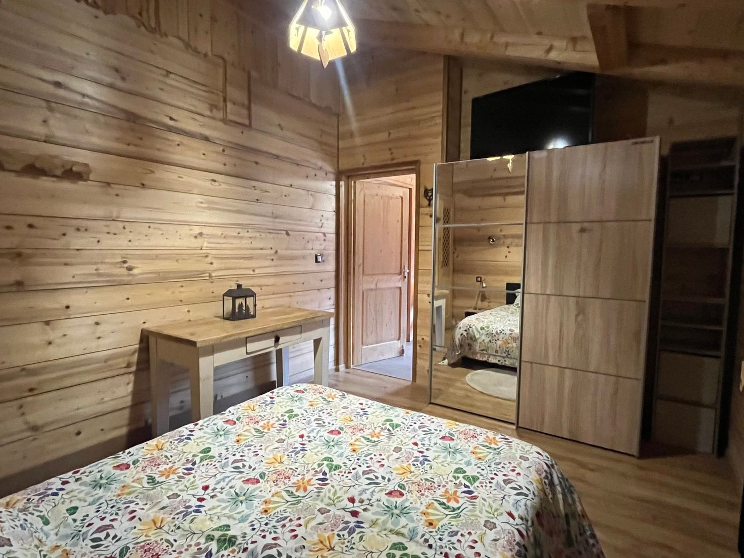 Una habitación de madera con una cama, un escritorio y un armario.