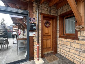 Un bâtiment en pierre avec une porte en bois, une boîte aux lettres et une couronne de Noël.