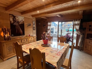 A wooden interior with a dining table, chairs, a fireplace, and a large deer painting.