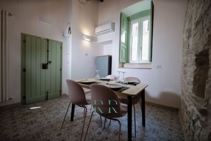Un comedor con una puerta verde, una ventana con contraventanas verdes y una pared de piedra.