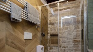 Ein Badezimmer mit Fischgrätparkett, einem weißen Waschbecken, einer Toilette und einer Duschkabine.