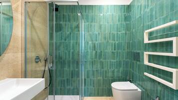 Un baño moderno con cabina de ducha de vidrio, un lavabo blanco y un inodoro.