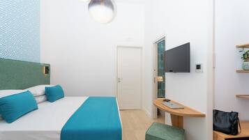 Een moderne hotelkamer met een bed, bureau, televisie en deur.