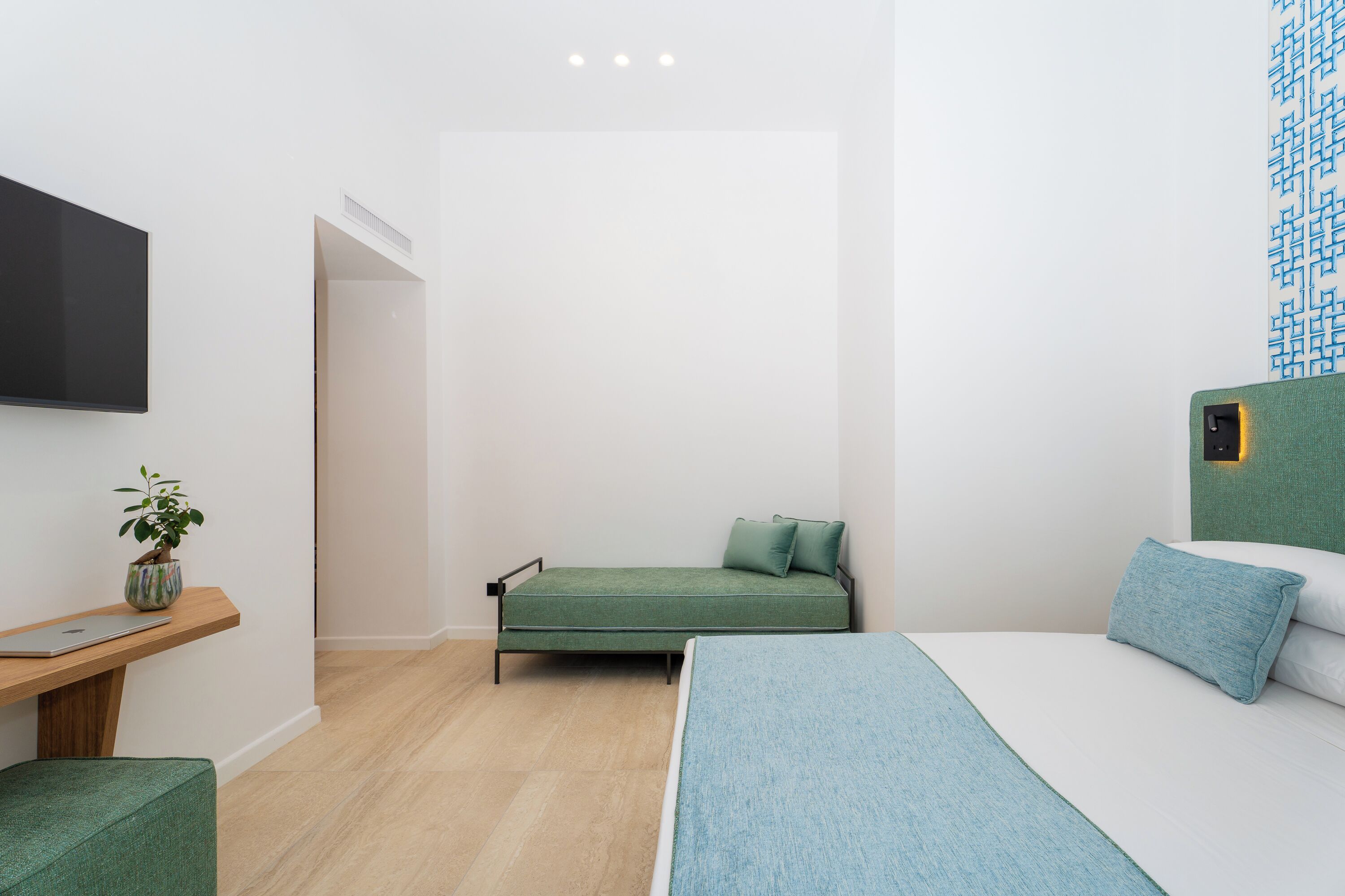 Una camera da letto moderna con un letto, una scrivania e una televisione.