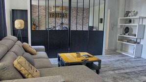A modern living room with a sectional sofa, a small coffee table, and a bookshelf. - The Loft Factory 4 Bedrooms Garonne View + Garden (Lormont)