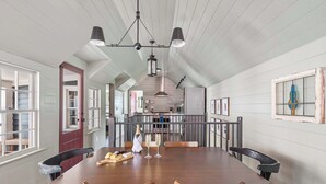 Un comedor con una gran mesa de madera, sillas e iluminación colgante.