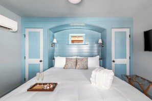 A bedroom with a blue wall, a white bed, two pillows, a tray with glasses and a plate, and a TV on the wall. - Private & Upgraded 3bd w. Parking, 1 block to King St! (Charleston)