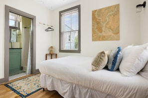A bedroom with a bed, a map on the wall, a window with blinds, and a door leading to a bathroom. - Downtown 3bd Home, Steps to King St! (Charleston)