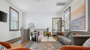Una sala de estar moderna con un sofá, sillones, una mesa de centro y un cuadro grande en la pared.