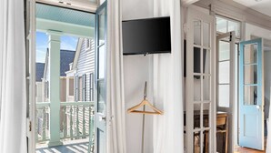 A room with a wooden floor, a TV mounted on the wall, and a wooden hanger. - Incredible 4bd House, 1 block to King w. Parking! (Charleston)