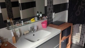 Une salle de bain moderne avec un grand lavabo, un miroir et un meuble-lavabo en bois.
