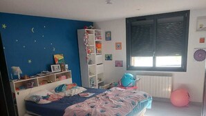 Une chambre avec un lit, une armoire, une fenêtre avec des stores et un mur décoré d’étoiles.