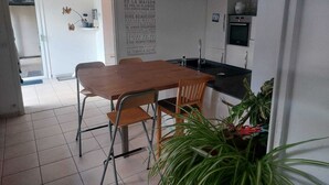 Une petite cuisine moderne avec une table et des chaises en bois, un réfrigérateur et un évier.
