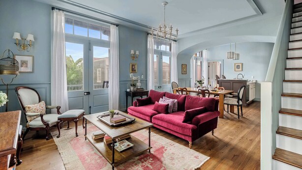 A spacious living area with a red sofa, wooden coffee table, and a dining table with chairs.