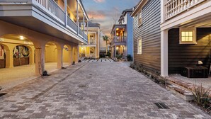 A courtyard with a cobblestone path, wooden buildings with balconies, and a clear sky.
