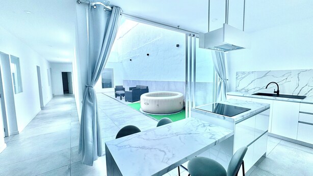 A modern kitchen with a built-in stove, a sink, and a dining area with a marble table. - The White House (Santa Lucía de Tirajana)