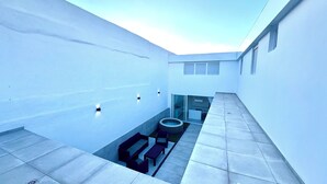 A modern rooftop terrace with a hot tub, seating area, and glass doors leading to an indoor space. - The White House (Santa Lucía de Tirajana)