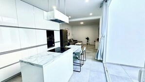 A modern kitchen with white cabinetry, a marble countertop, and a built-in oven. - The White House (Santa Lucía de Tirajana)