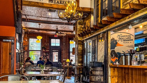 A restaurant interior with wooden floors, a bar area, and a sign indicating 'Main St.' - Elk Creek Farmhouse near Penn State! (Millheim)