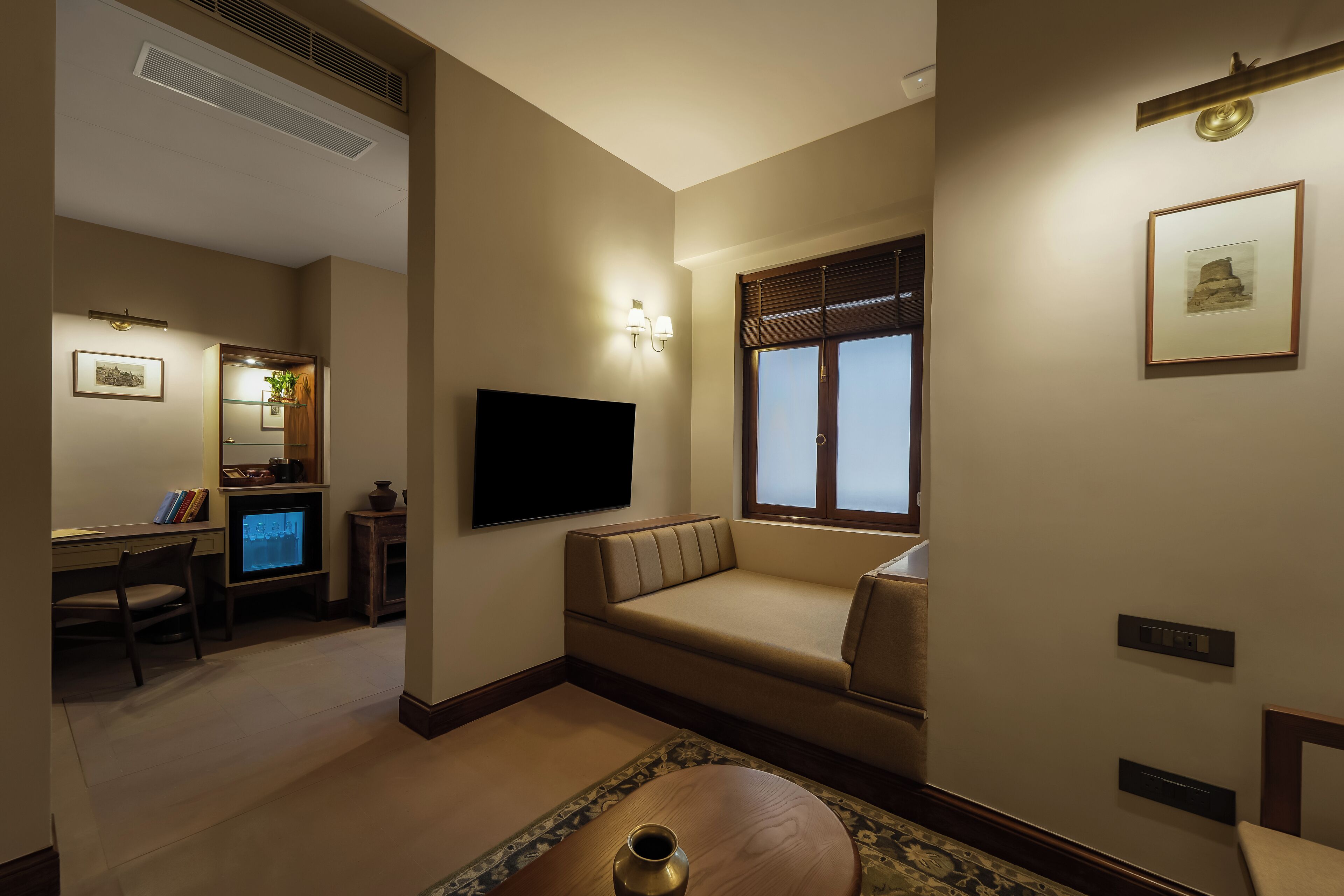 A living room with a sofa, a TV, a small table, and a window with blinds.