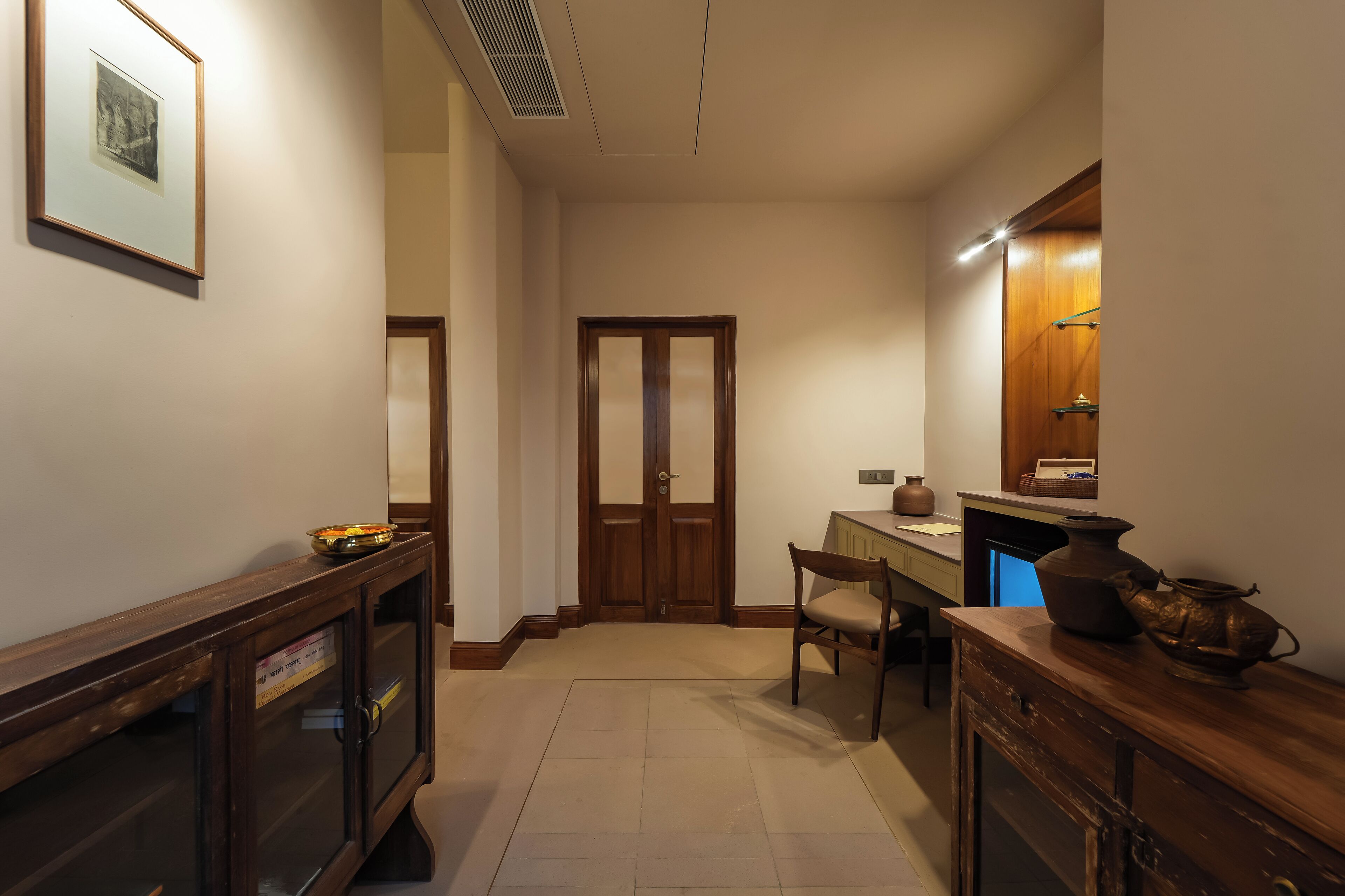 Un couloir avec une armoire en bois, une chaise, un bureau et une porte.