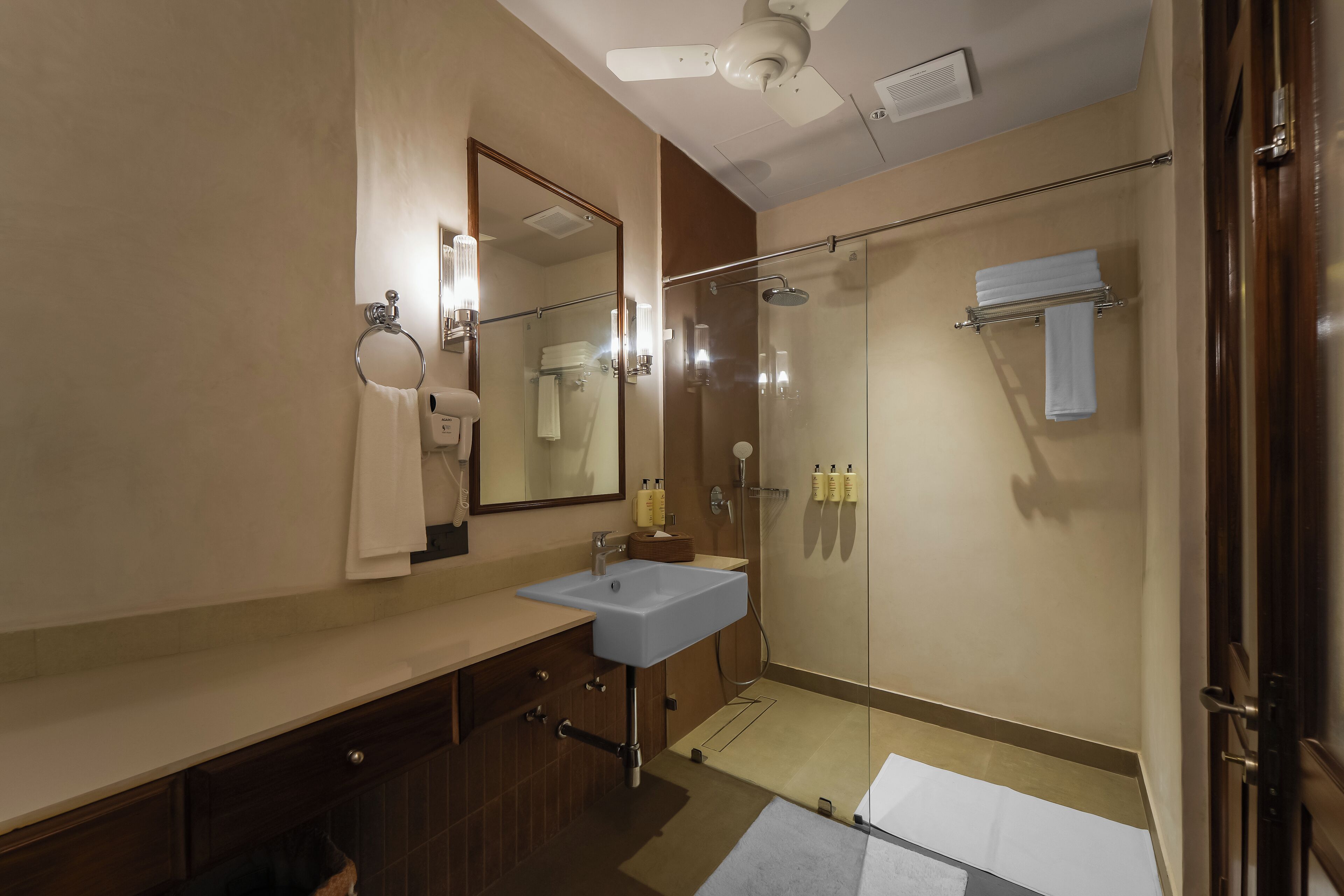 Een moderne badkamer met een grote spiegel, een wastafel, een douche en een handdoekhouder.