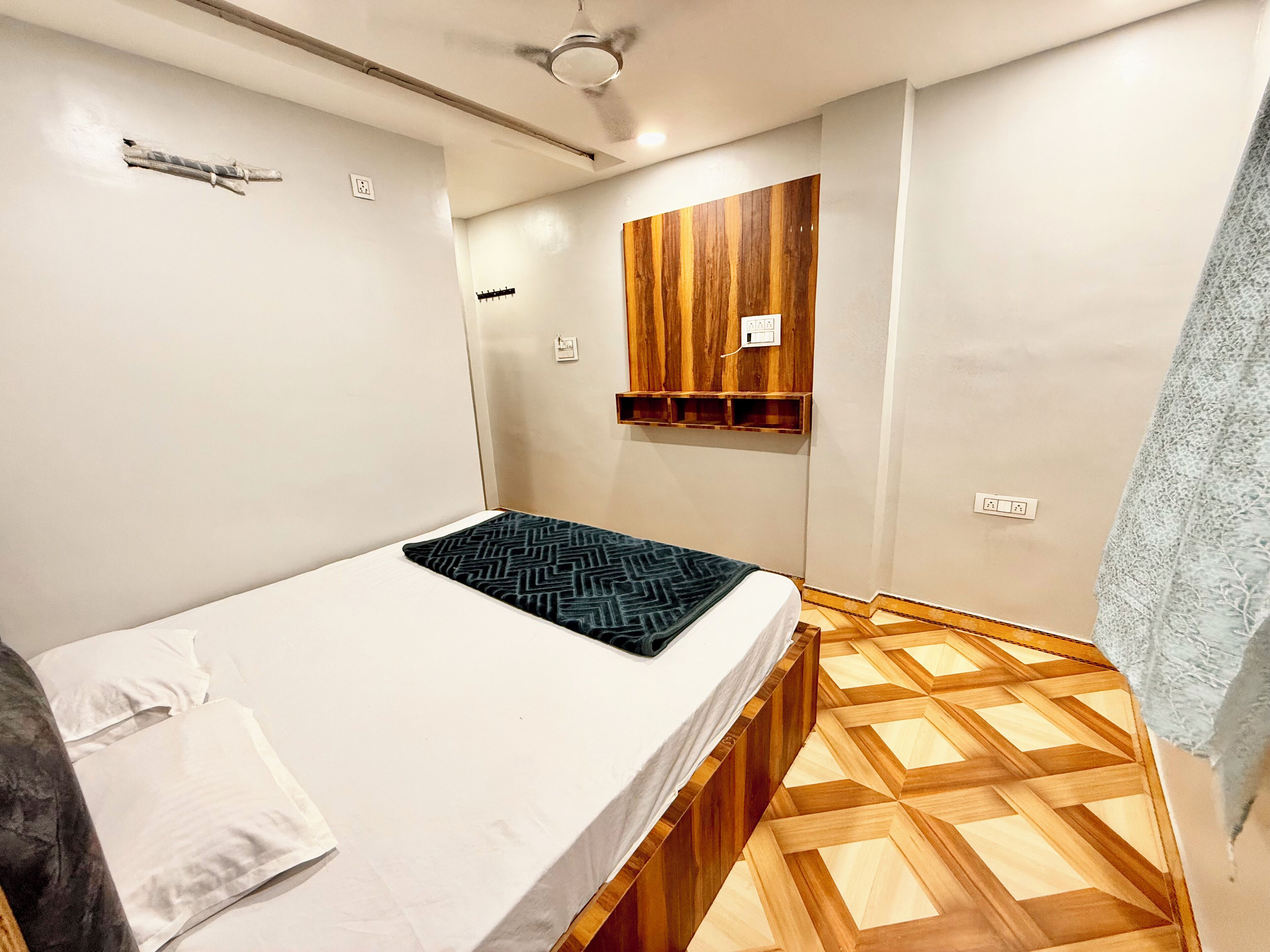A small, modern bedroom with a bed, a wooden cabinet, and a patterned floor.
