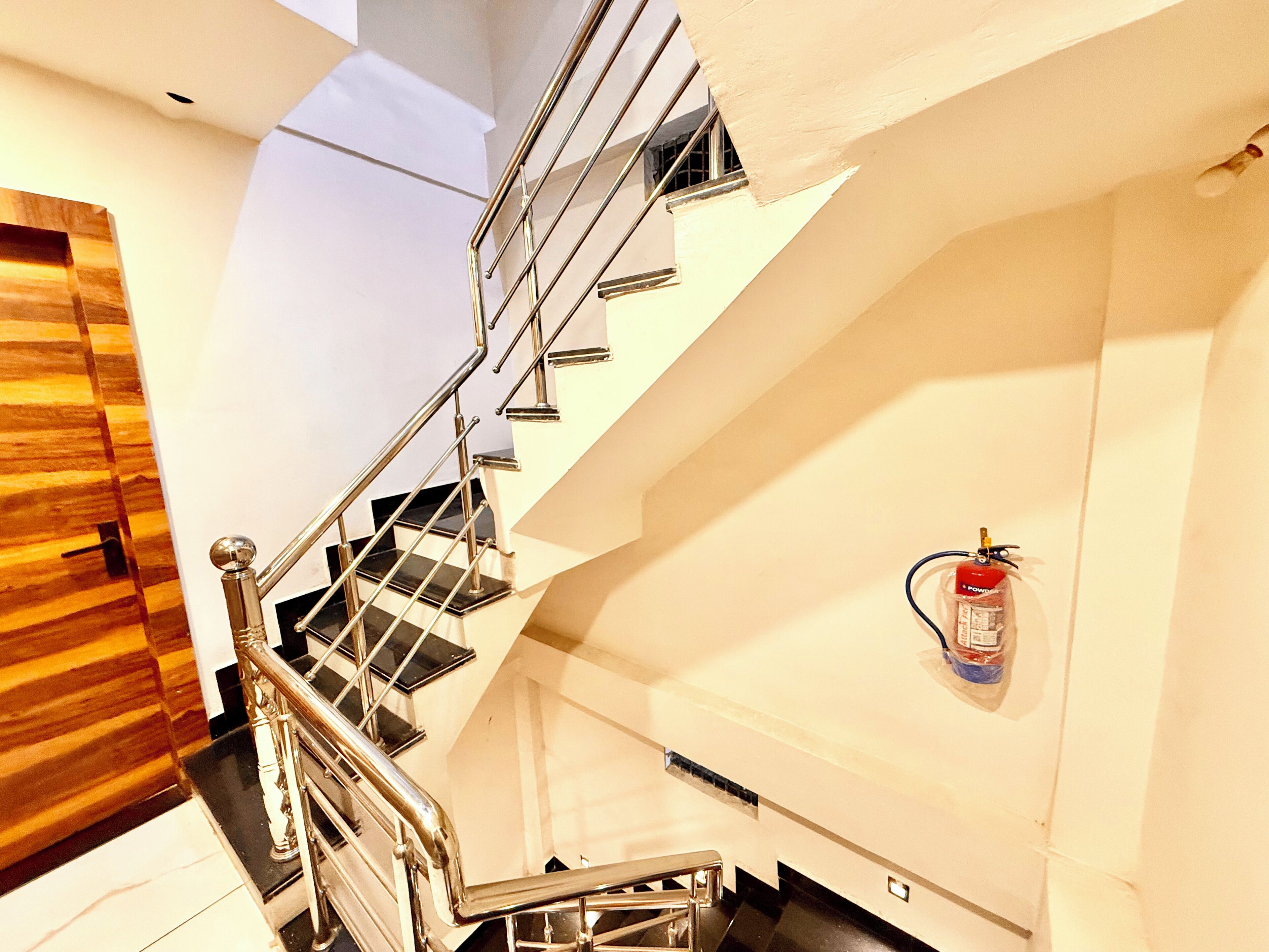A modern staircase with metal railings and a fire extinguisher mounted on the wall.