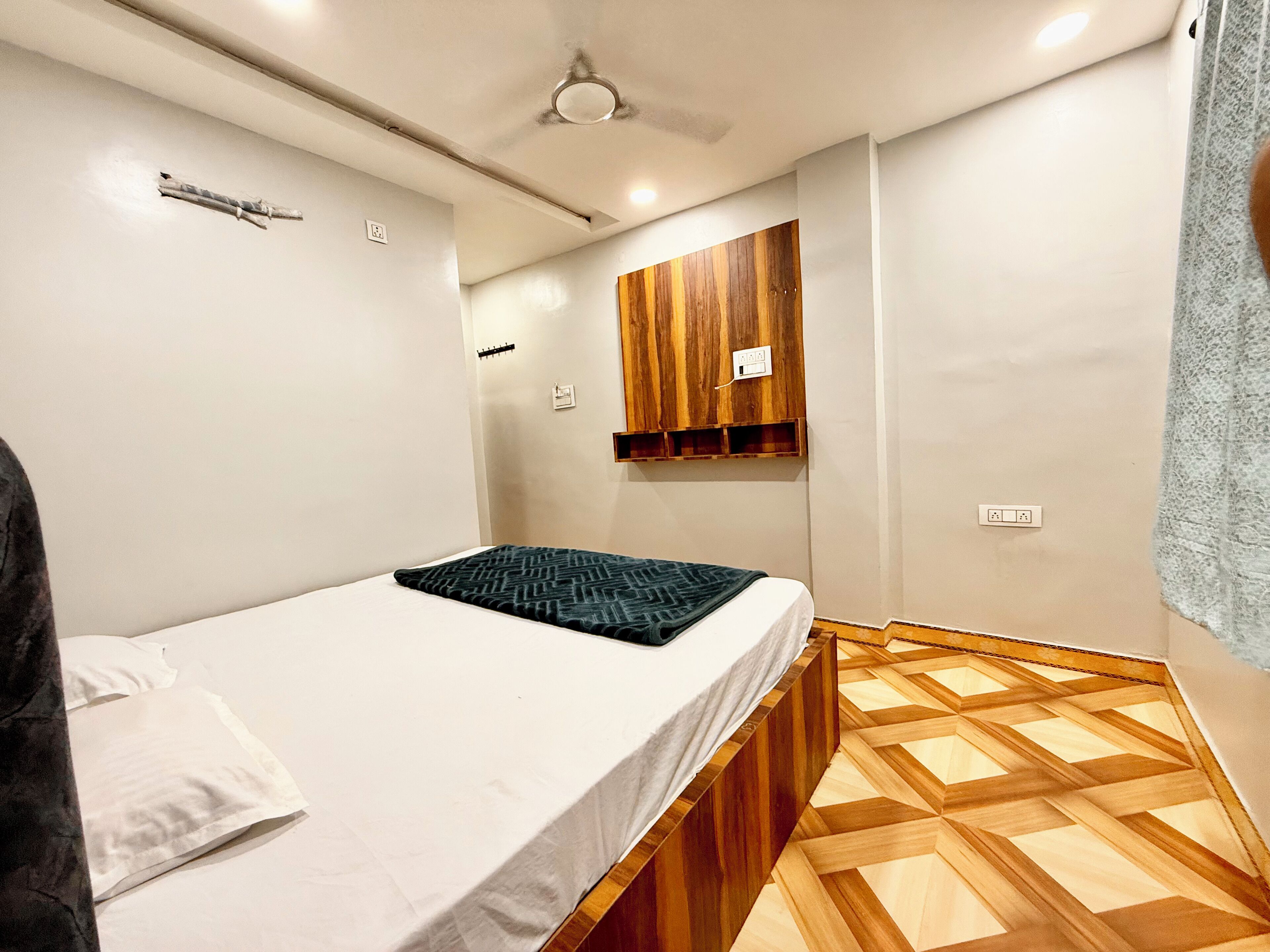 A bedroom with a bed, wooden wardrobe, and a patterned floor.
