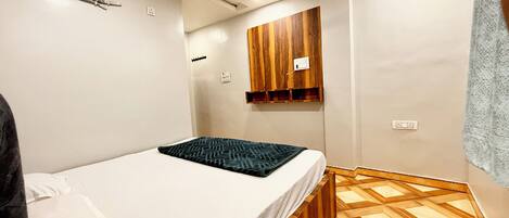 A bedroom with a bed, wooden wardrobe, and a patterned floor.