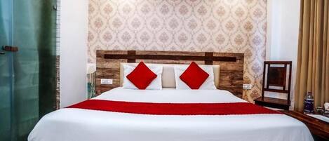 A hotel room with a large bed, a wooden headboard, and a patterned wallpaper.