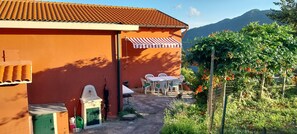 A building with a tiled roof and a small patio area with outdoor furniture. - ANITA B&B  (Uscio)